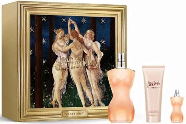 Jean Paul Gaultier Classique gift set featuring a gold-framed box with an artistic illustration of three women dancing under stars. In front of the box are the Classique torso-shaped perfume bottle, a matching body lotion, and a mini travel spray