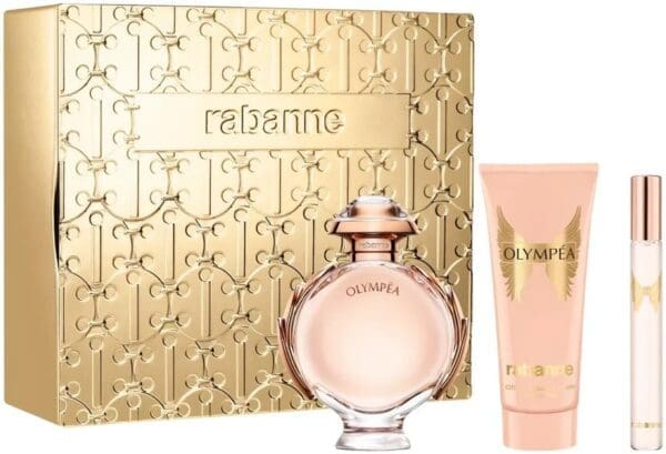 Rabanne Olympea gift set displayed in front of a gold embossed box. The set includes the round Olympea perfume bottle with rose-gold details, a matching pink body lotion with gold wings, and a slim travel spray.